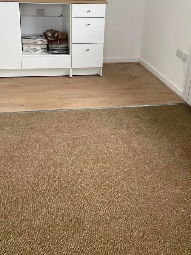 Tan carpet meeting laminate at a neat doorway threshold