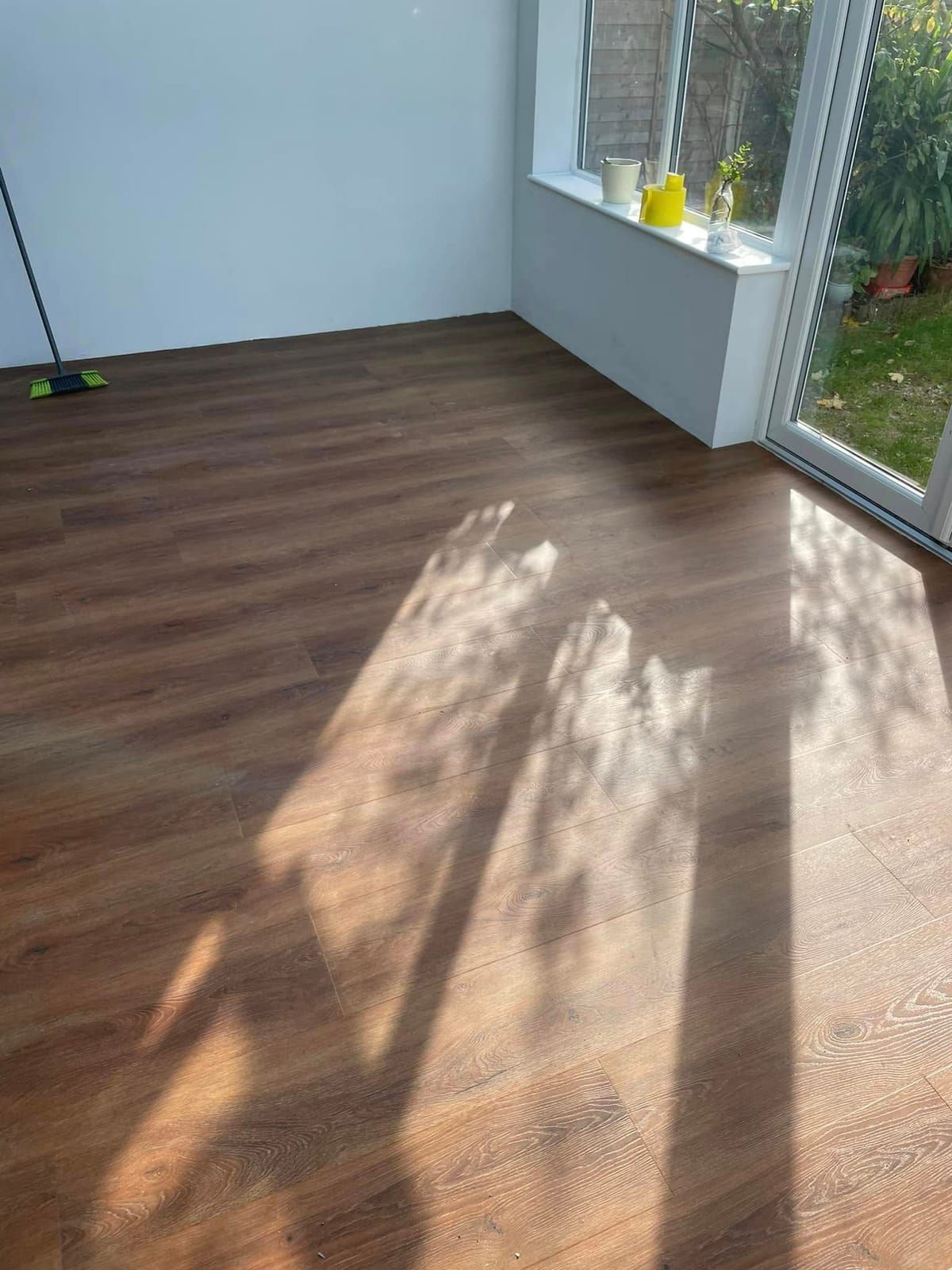 Warm oak-effect plank floor in a garden room in afternoon sun