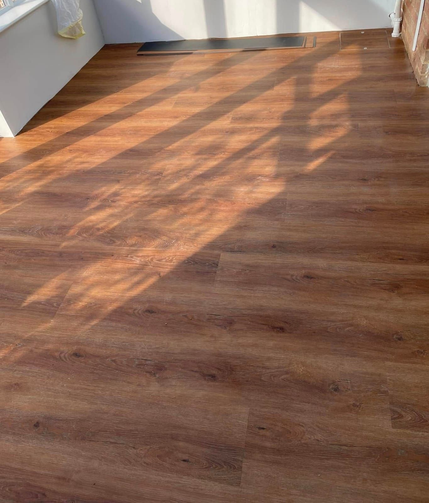 Oak-effect plank floor with sunlight across the boards