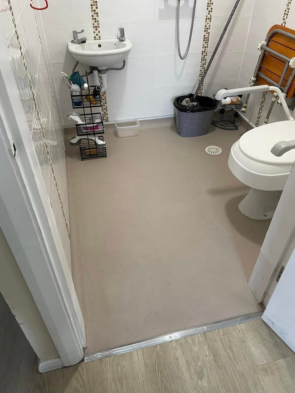 The same bathroom finished in grey slip-resistant safety vinyl, with grab rails fitted
