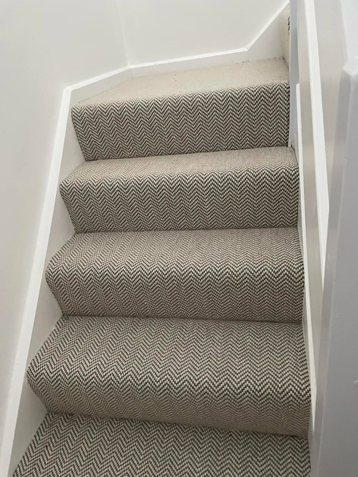 Grey herringbone carpet on a closed staircase with rounded bullnose steps