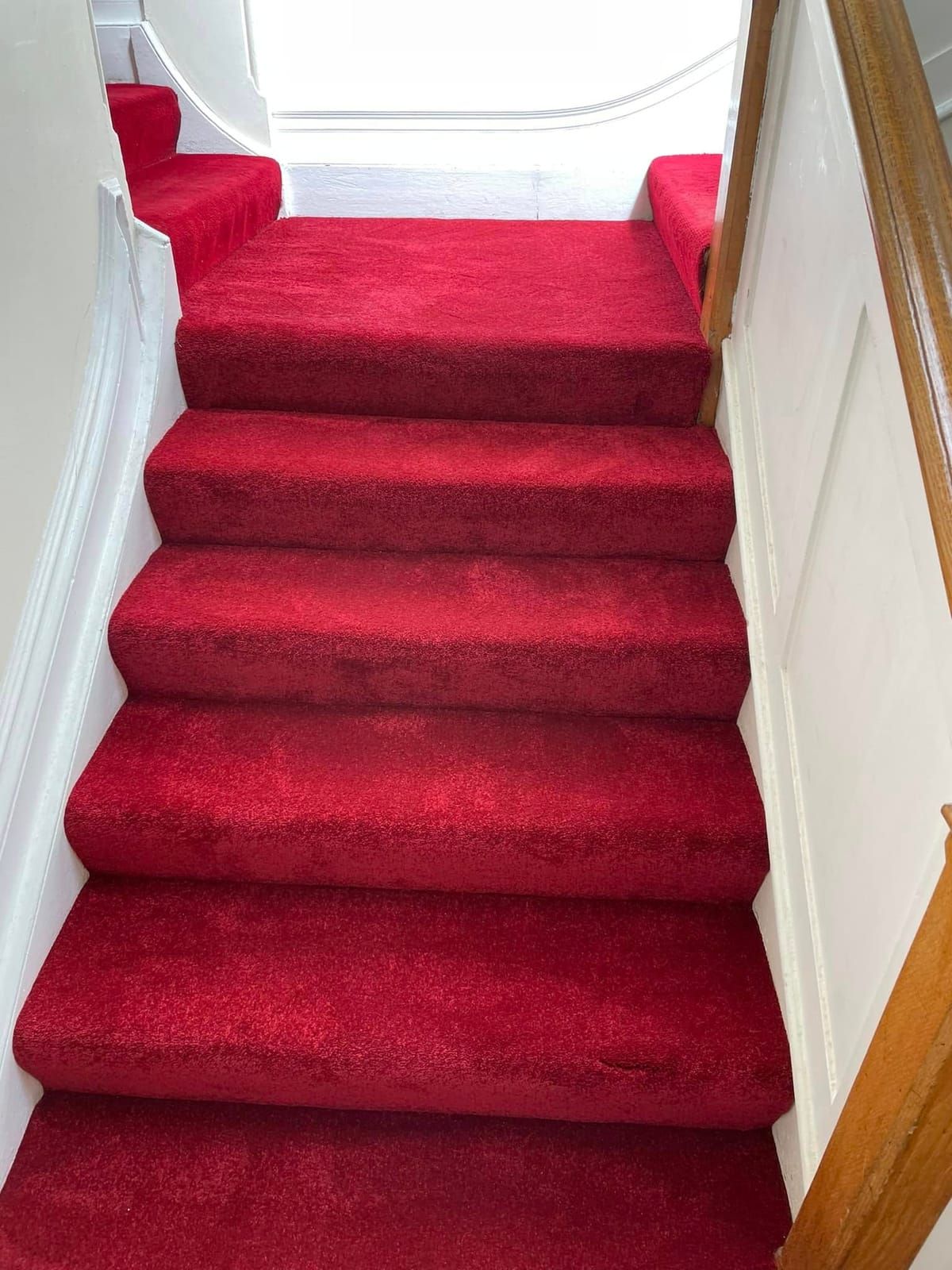 Red carpet staircase seen from the hallway, fitted tight to every tread