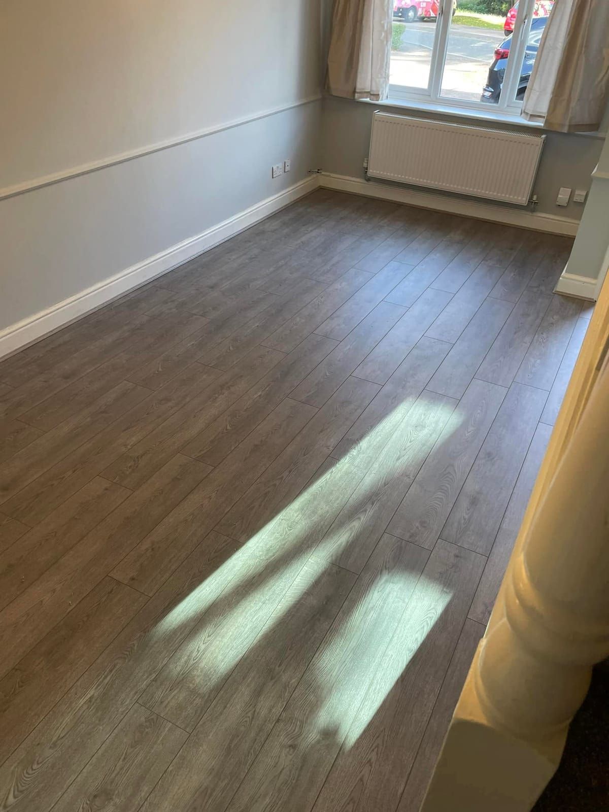 Dark oak plank floor in a sunlit empty room